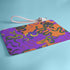 Rectangular wristlet clutch featuring vibrant purple and orange background with colorful snake prints. White strap and gold zipper visible.